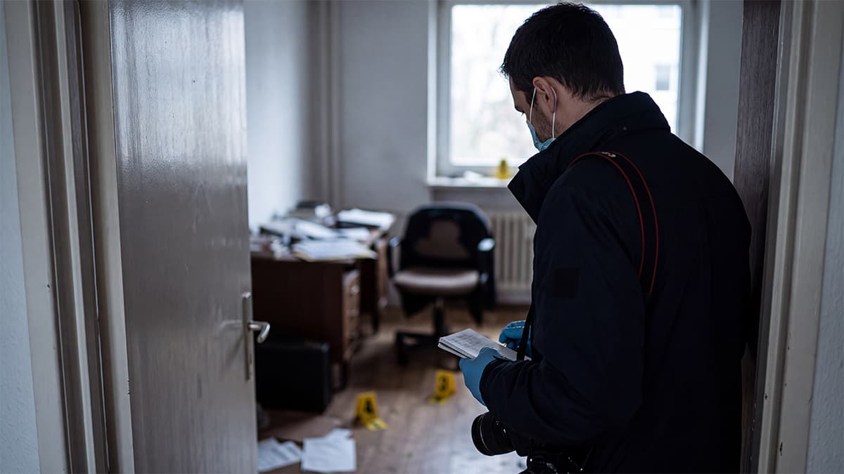 Crime scene investigator observing and documenting evidence at a scene.